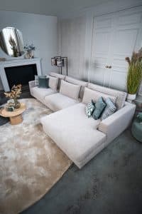 Hoekbank Claire in een lichte stof. Interieurstyling met hippe beige en petrol woonaccessoires.