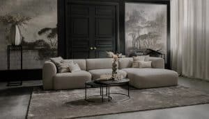 Elementenbank Emanuelle met een longchair. Uitgevoerd in een lichte beige stof. Gecombineerd met een groot vloerkleed en naturel decoratie.